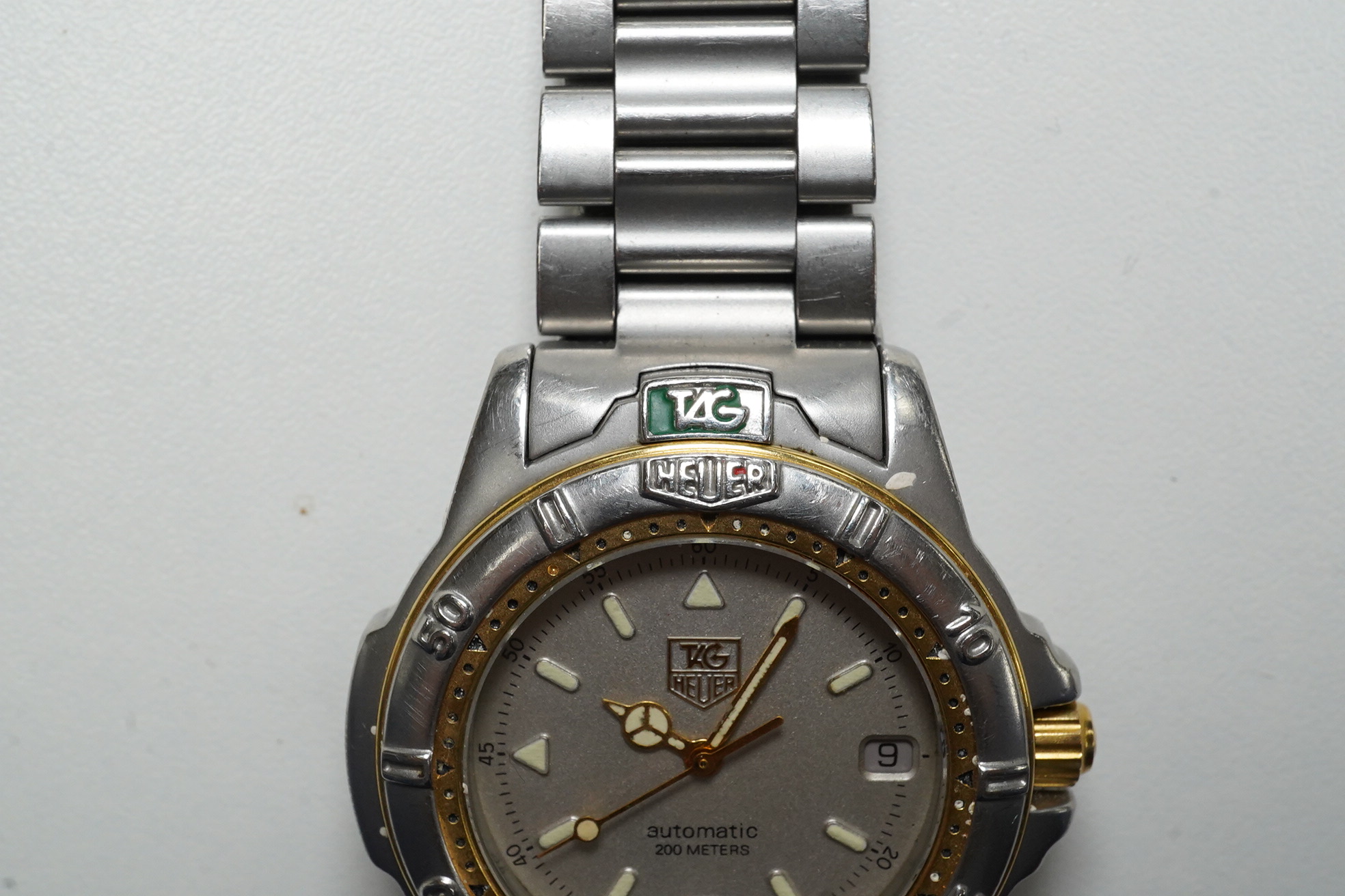 A gentleman's stainless steel Tag Heuer automatic wrist watch, with baton numerals and date aperture, case diameter 38mm, together with a battery operated winder. Condition - poor to fair